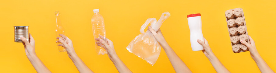 Close up hands hold set of recycling paper plastic glass metal objects isolated on yellow background. Stop nature garbage, ecology environment protection concept. Save planet Packaging template mockup